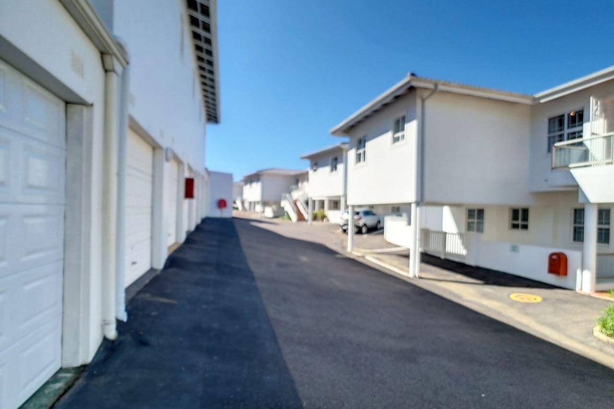 A view of the complex driveway featuring multiple garage doors and residential building facades with white exterior finishes.