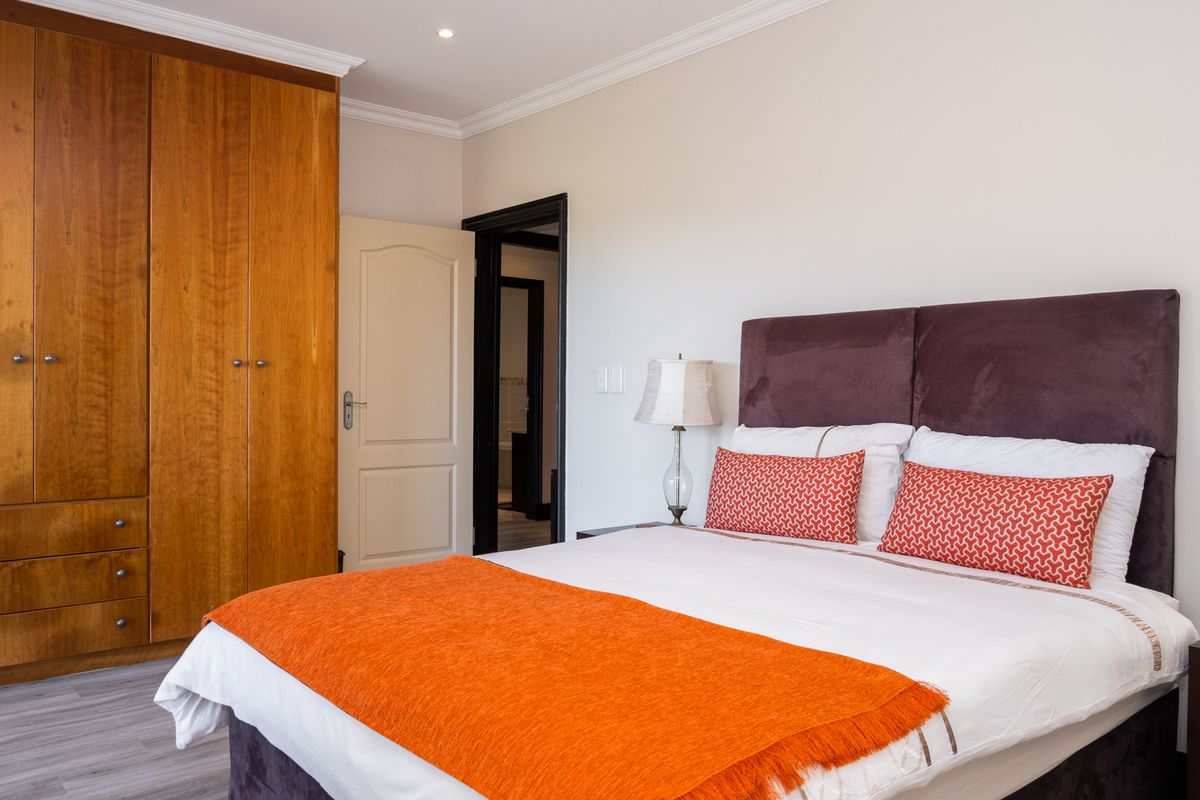 A well-maintained bedroom featuring built-in wooden cabinetry, crown molding, and direct access to an adjoining bathroom.