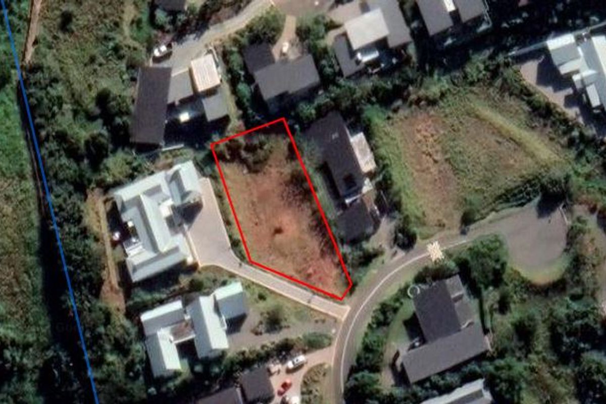 An aerial view of a vacant residential land parcel outlined in red, situated within an established neighborhood.