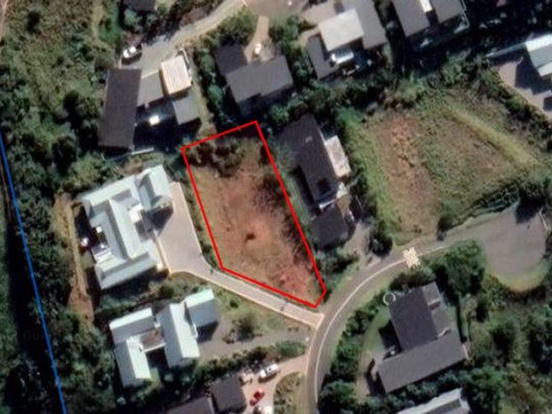 An aerial view of a vacant residential land parcel outlined in red, situated within an established neighborhood.
