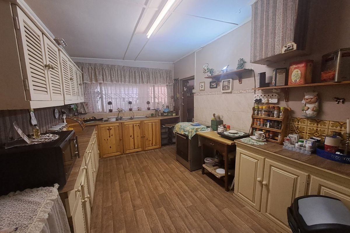 A dated kitchen featuring wooden cabinetry, laminate countertops, and a tiled splashback, offering a functional layout with potential for modernization.