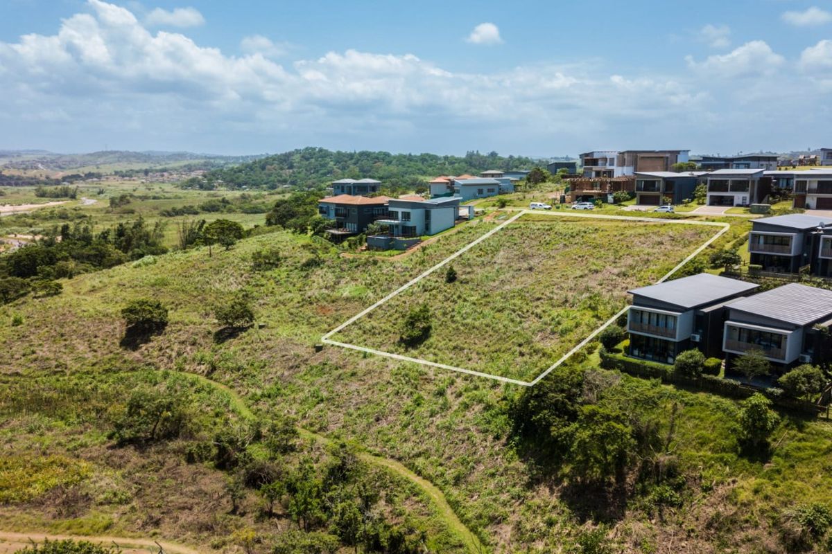 An aerial view of a vacant residential plot situated on a hillside within a developed estate, offering potential for custom home construction.