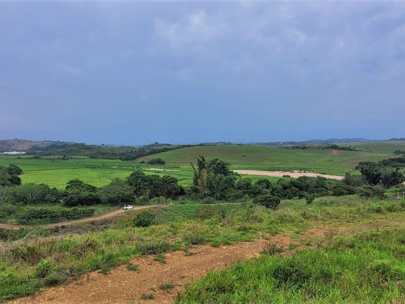 A scenic elevated view overlooking expansive green rolling hills and natural landscape, showcasing the property's tranquil surroundings.
