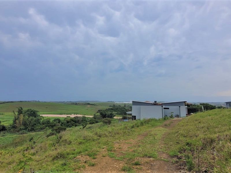A wide-angle view of the expansive green landscape and rolling hills surrounding the residential property.