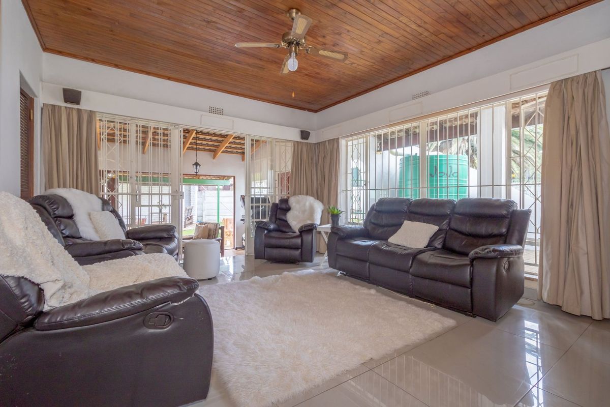 Spacious living room featuring a warm timber ceiling, ceiling fan, tiled floors, and large sliding doors providing access to the outdoor patio area.