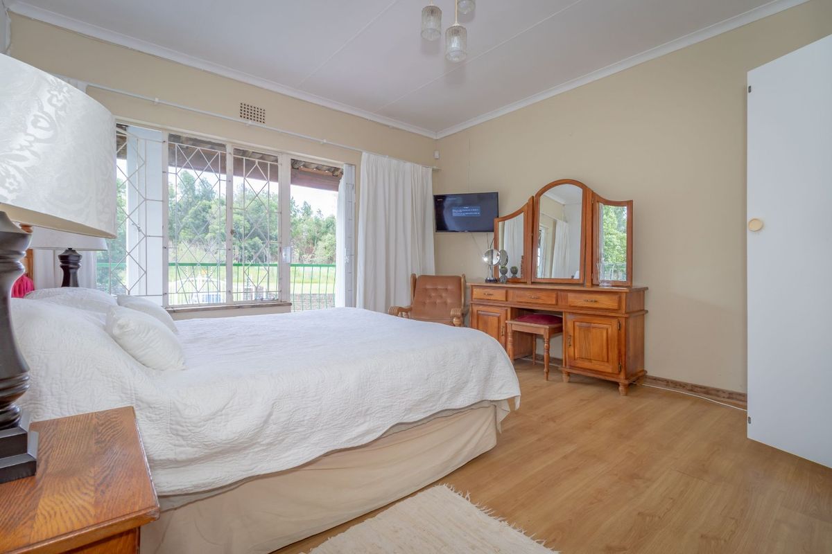 A bedroom featuring laminate flooring, built-in cupboards, and a sliding door providing access to an outdoor area.