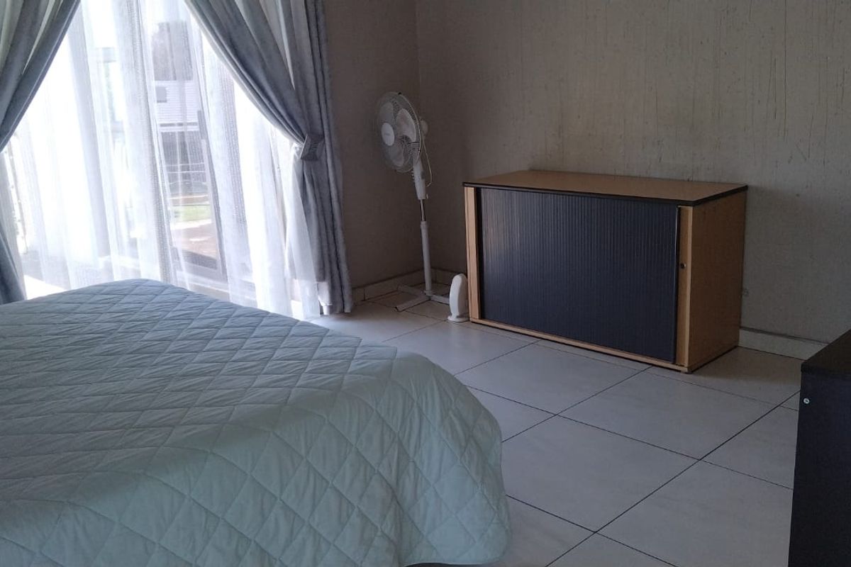 A bedroom featuring tiled flooring and large sliding glass doors providing natural light and access to the exterior.