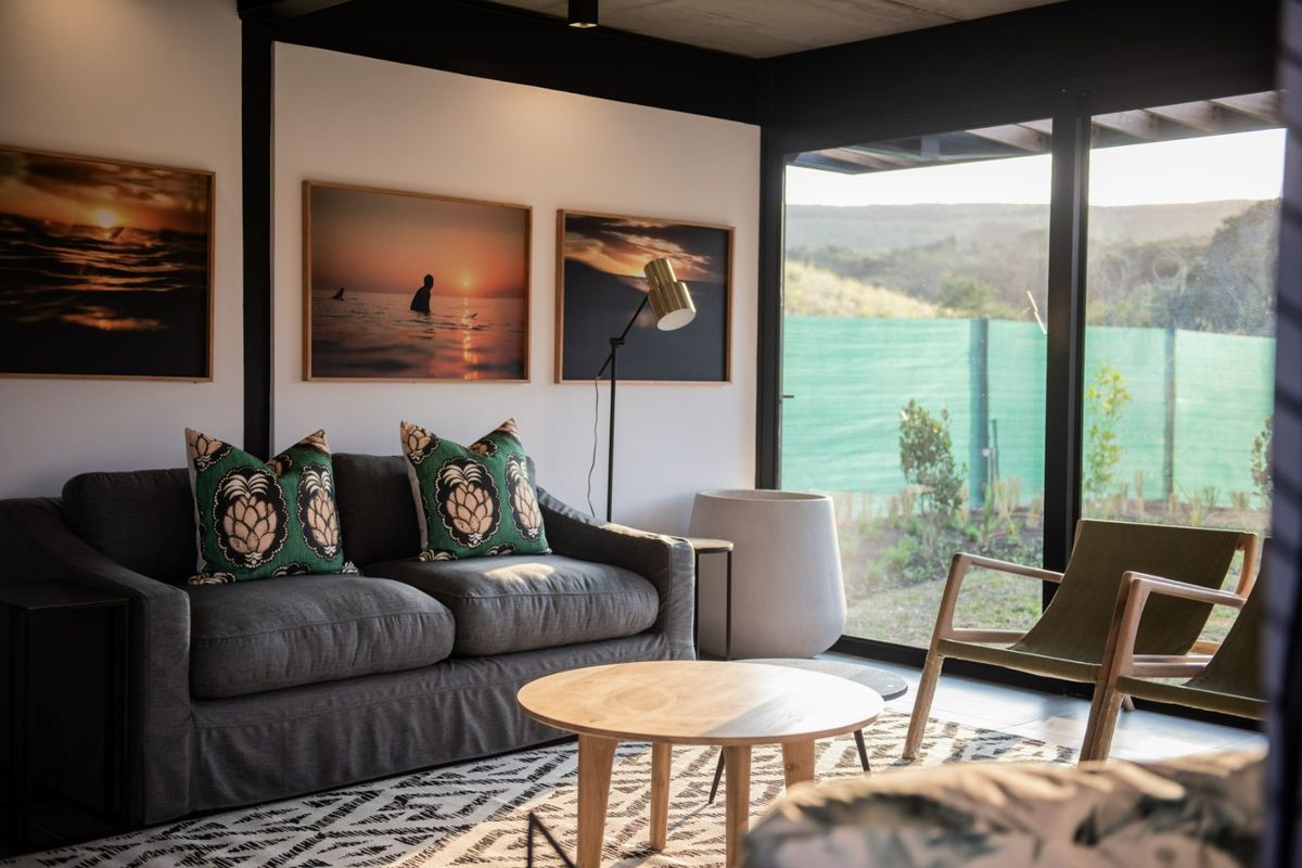 A modern living room featuring large floor-to-ceiling glass sliding doors that provide abundant natural light and a seamless connection to the outdoor garden area.