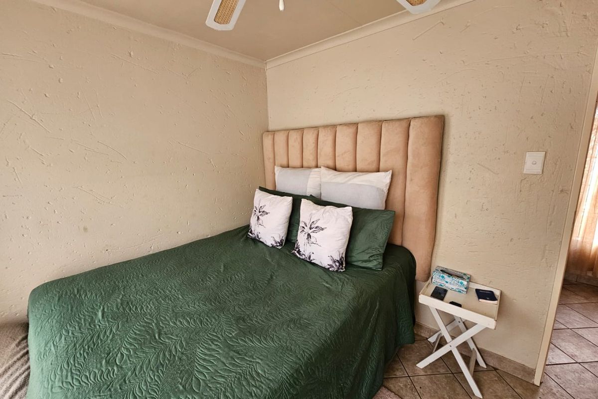 A bedroom featuring textured walls, tiled flooring, and a ceiling fan.