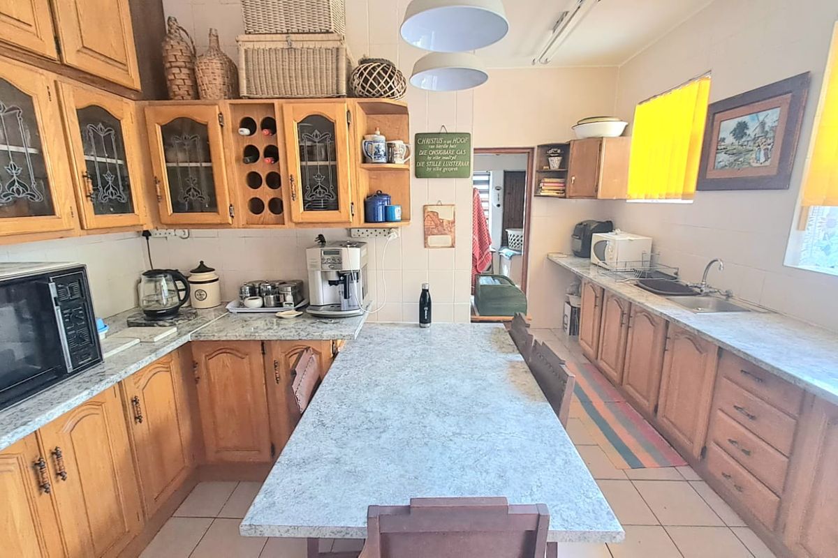 A functional kitchen featuring traditional wooden cabinetry, laminate countertops, a central breakfast island, and tiled flooring with ample storage space.