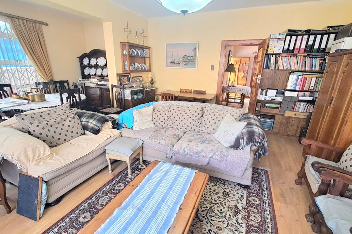 A spacious living room featuring laminate flooring, built-in shelving units, and access to an adjacent dining area.