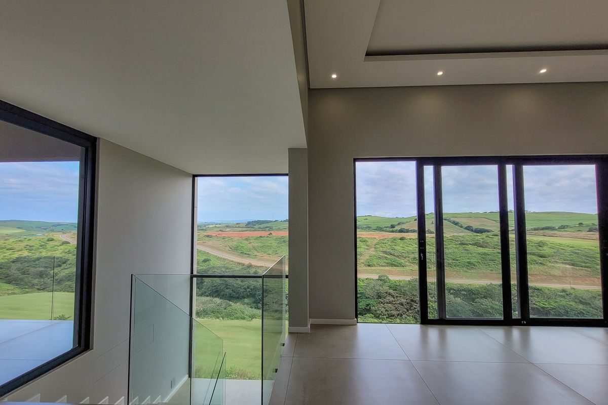 Spacious modern living area featuring large floor-to-ceiling windows, recessed ceiling lighting, and expansive views of the surrounding landscape.