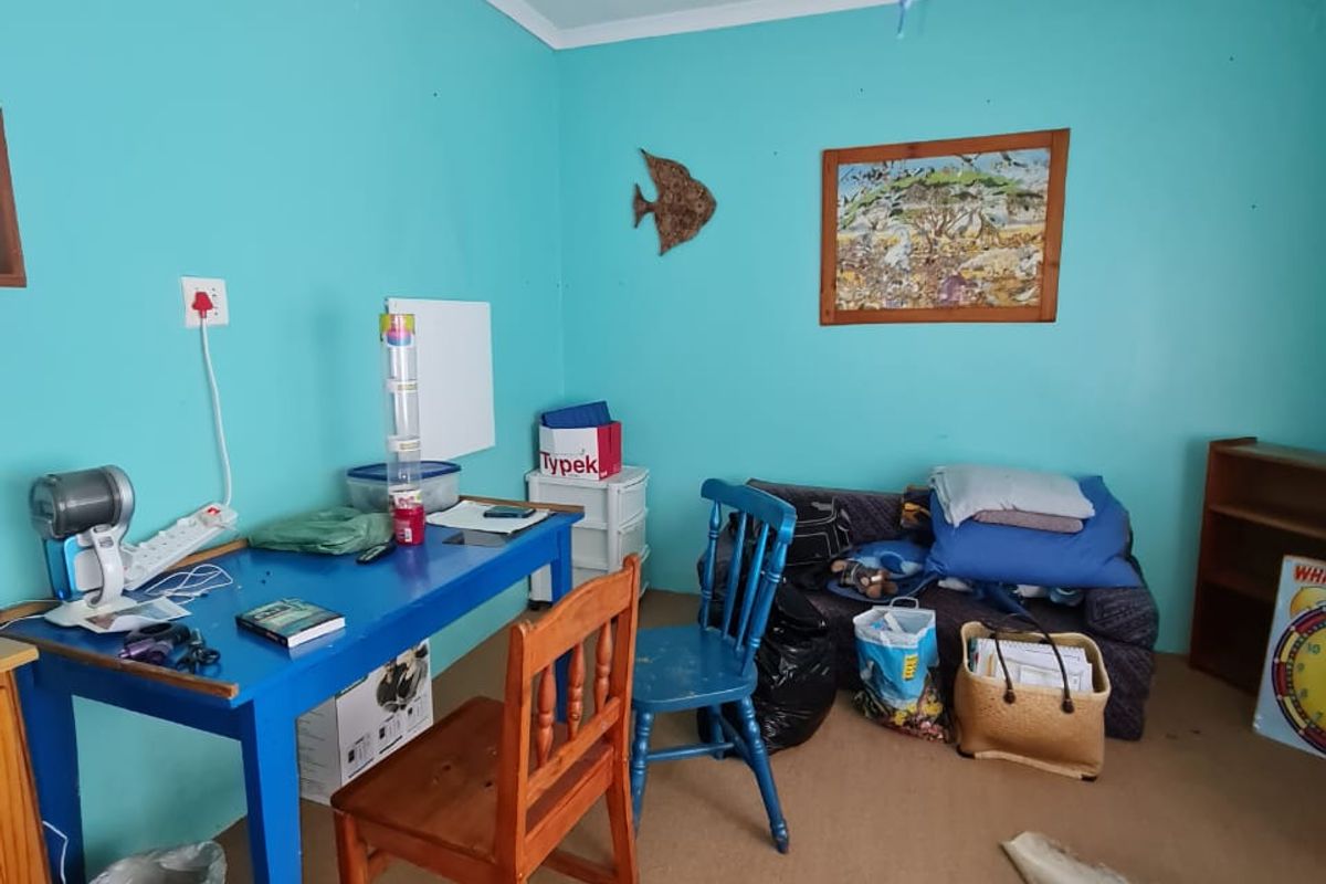 A small bedroom or study area featuring carpeted flooring and bright blue wall paint, suitable for a home office or guest room.