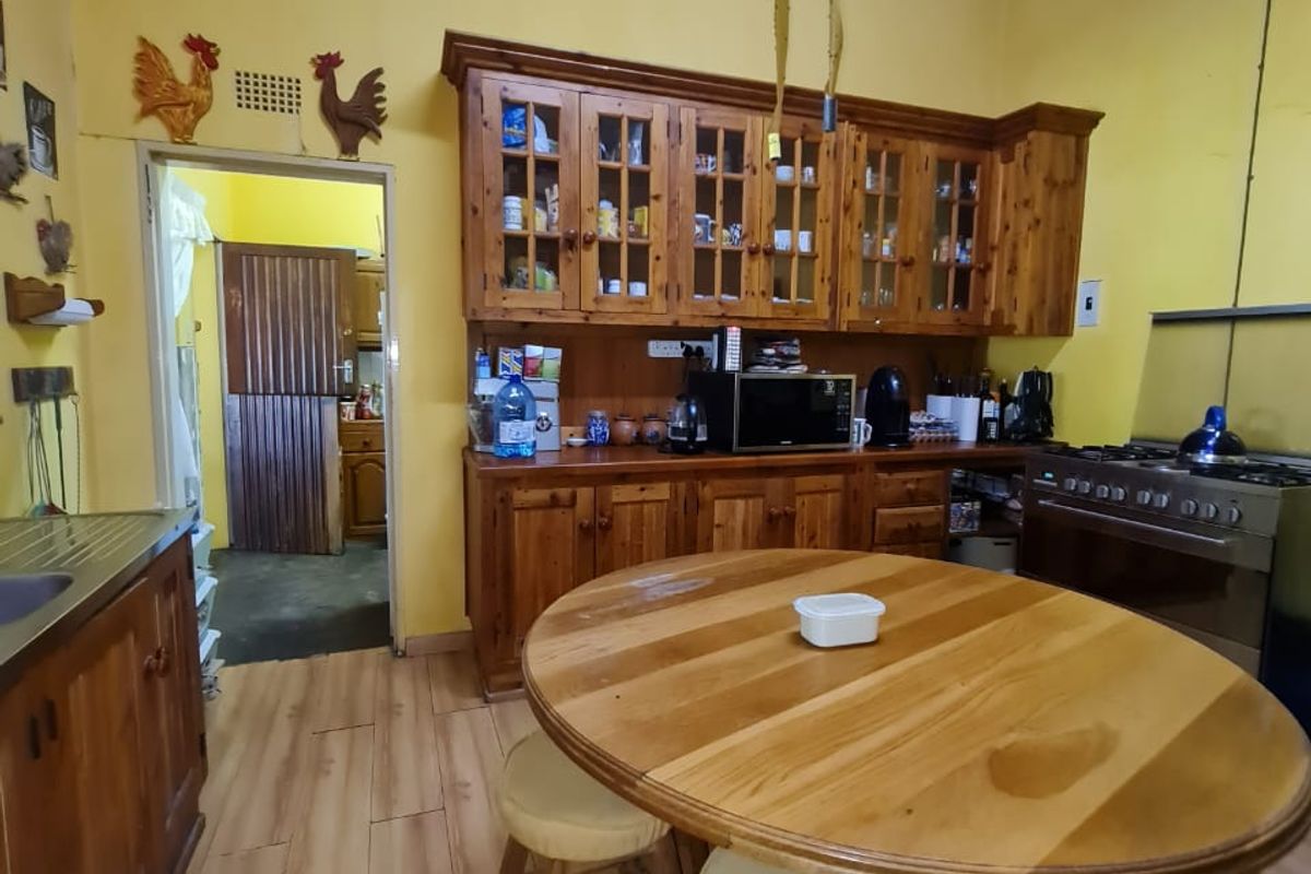 A rustic kitchen featuring wooden cabinetry, a built-in stove, and wood-look flooring, with an adjacent doorway leading to a secondary utility area.