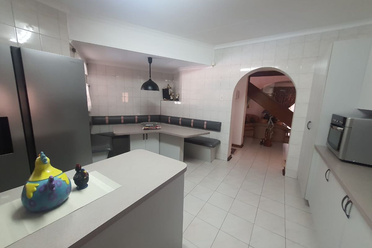 A functional kitchen featuring built-in cabinetry, tiled walls, and a dedicated breakfast nook area with integrated bench seating.