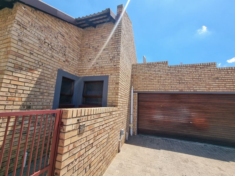 Front exterior view of the townhouse featuring a face brick facade, a paved driveway, and a secure sectional garage door.