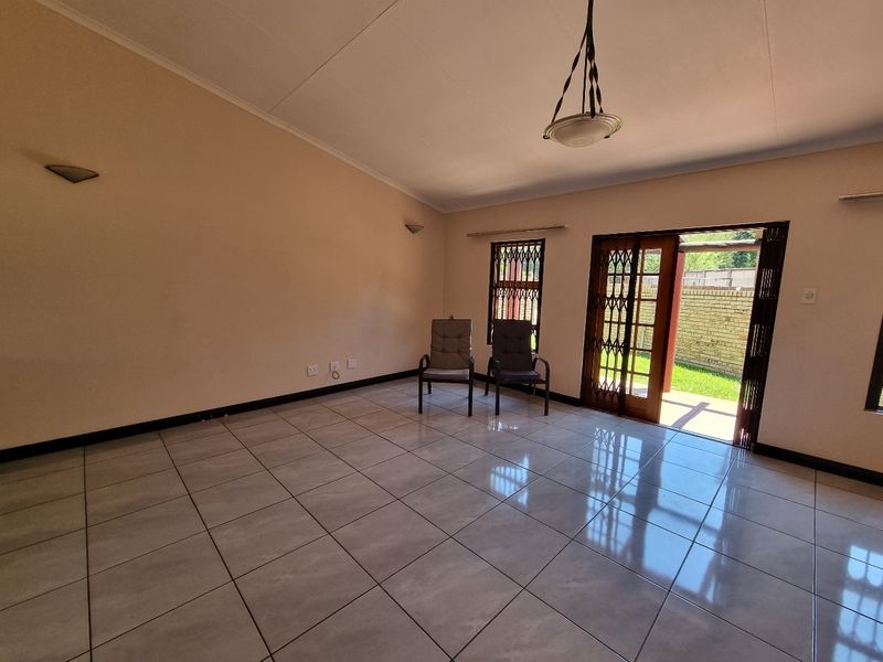 Spacious living area featuring neutral tiled flooring, ample natural light, and direct access to the outdoor patio through a secure sliding door.