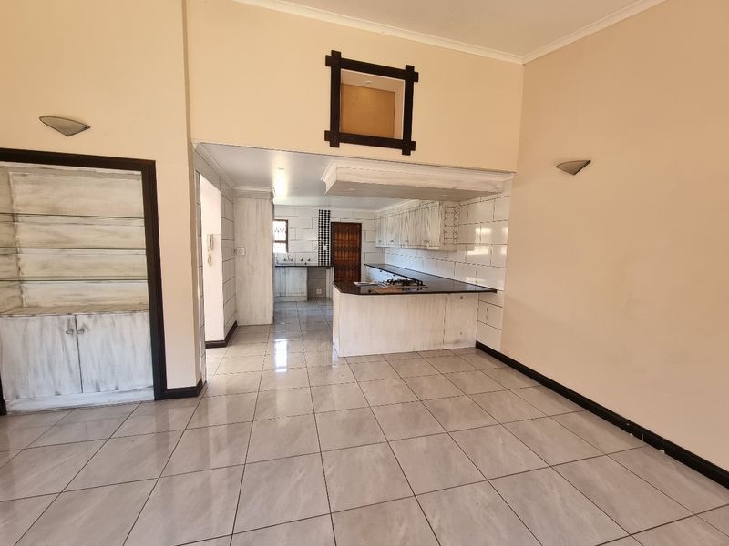 Open plan living and kitchen area featuring tiled floors, built-in cabinetry, granite countertops, and a gas hob in a neutral setting.