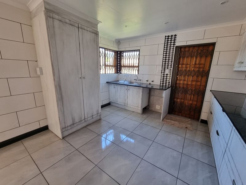 A functional kitchen featuring built-in cabinetry, granite countertops, and tiled flooring, providing a clean and practical workspace.