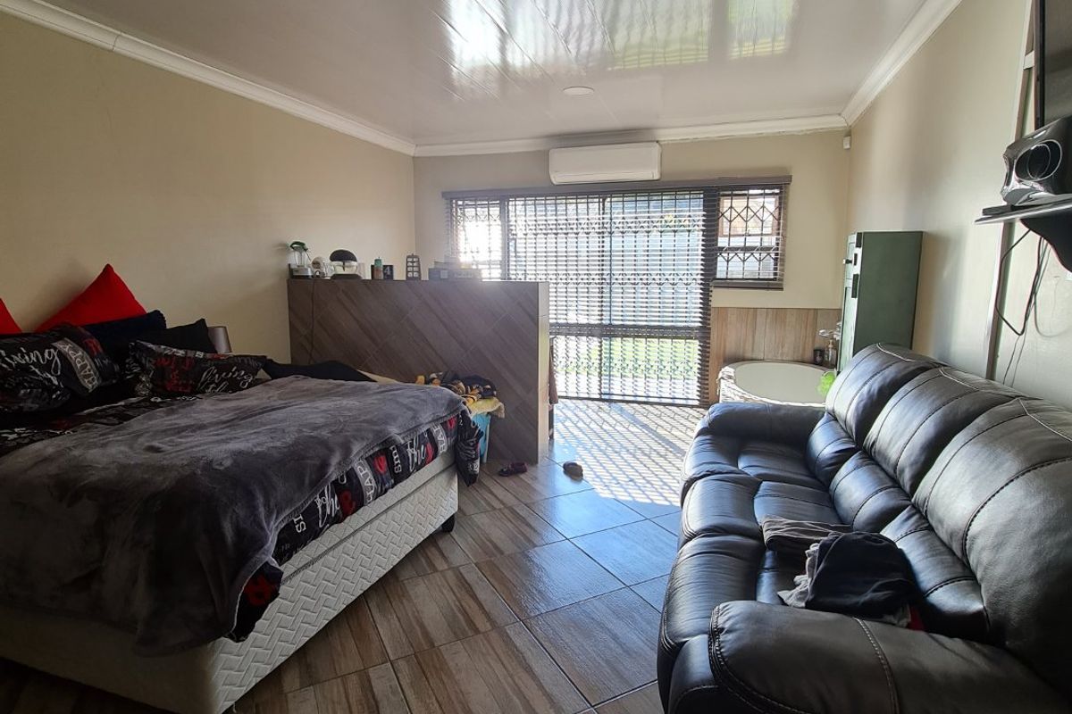 Spacious bedroom featuring tiled flooring, a split-system air conditioning unit, and a partition wall separating the sleeping area from a corner bathtub.