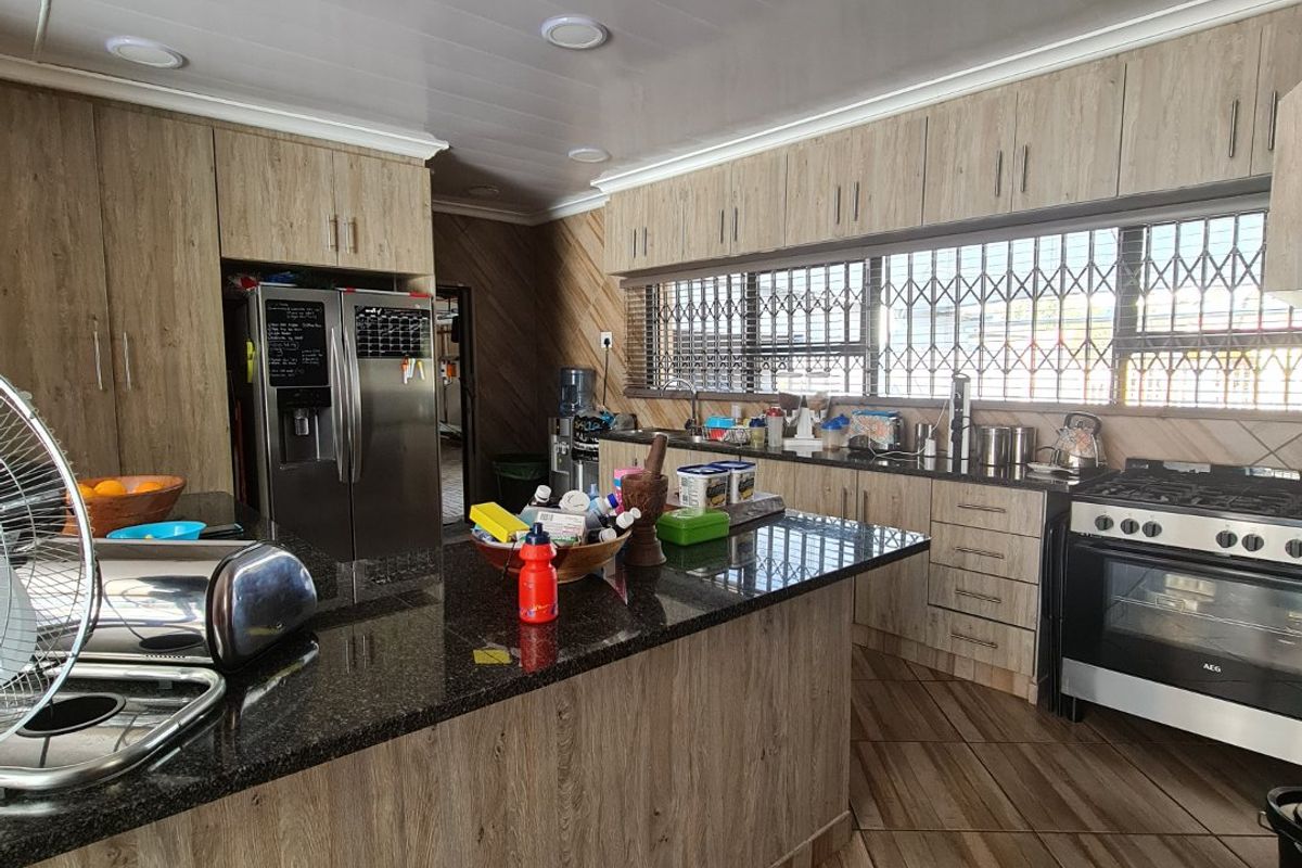 A functional kitchen featuring wood-look cabinetry, granite countertops, a central island, and a built-in gas stove with an oven.