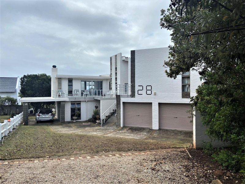 Front elevation of a multi-level house featuring a double garage, upper-level balcony, and concrete driveway access.