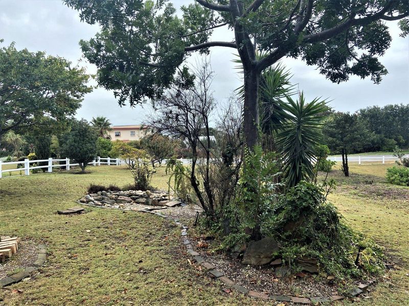 A spacious garden area featuring established trees, a rockery feature, and a white picket fence boundary.