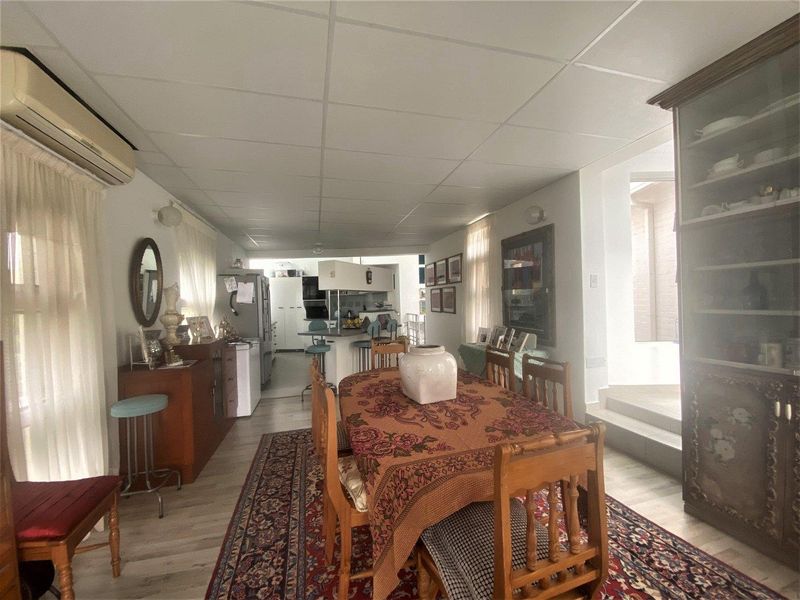 Open plan dining and kitchen area featuring laminate flooring, a central kitchen island, and a split-system air conditioner.