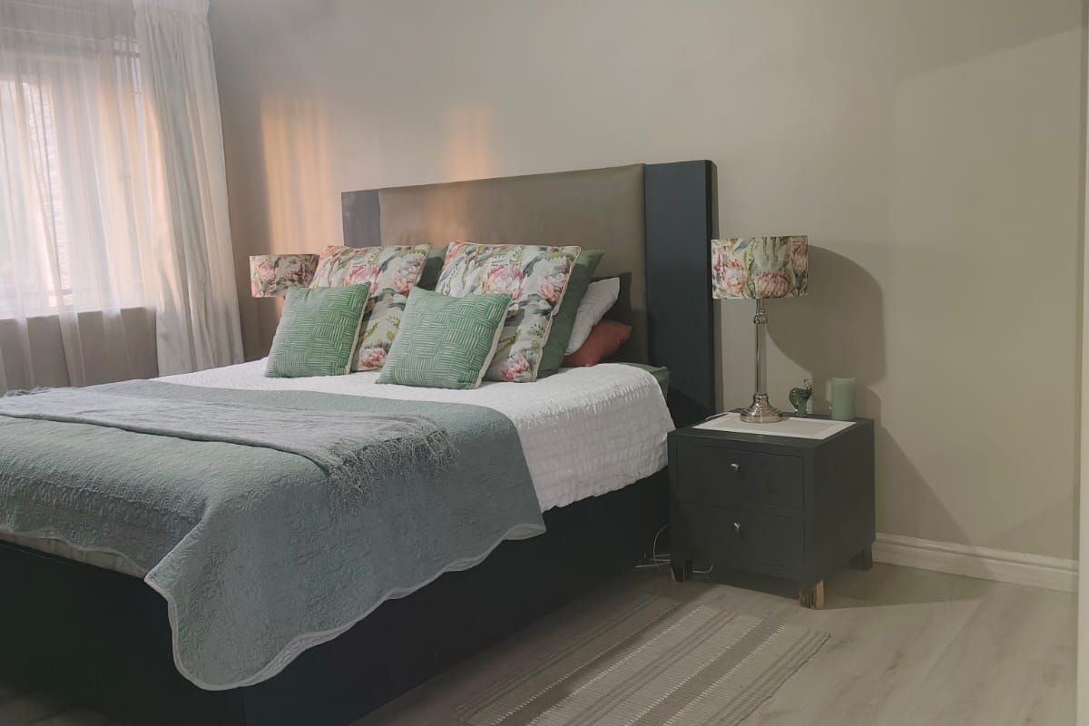 A well-maintained bedroom featuring light-toned laminate flooring, a ceiling fan, and neutral wall finishes, creating a comfortable and inviting sleeping space.