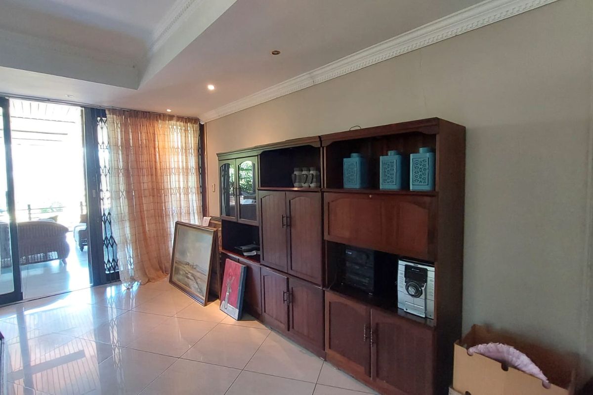 Spacious living area featuring polished floor tiles, decorative ceiling cornices, and large sliding glass doors providing access to an outdoor patio.