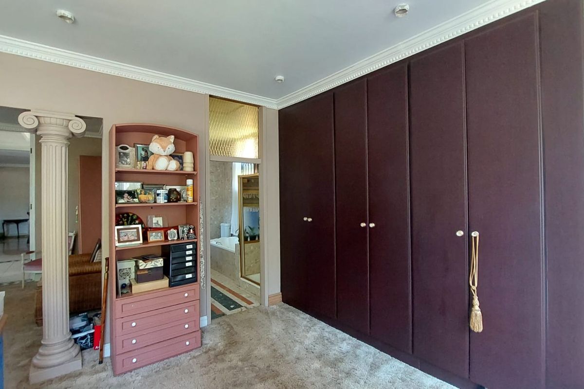 A bedroom featuring extensive built-in dark cabinetry and decorative crown molding, with an adjacent view into a bathroom area.