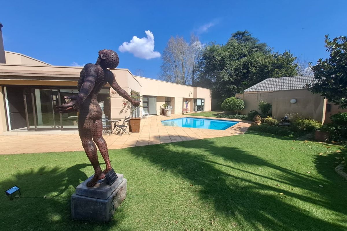 A spacious rear garden featuring a swimming pool, paved patio area, and well-maintained lawn, providing an ideal space for outdoor relaxation and entertainment.