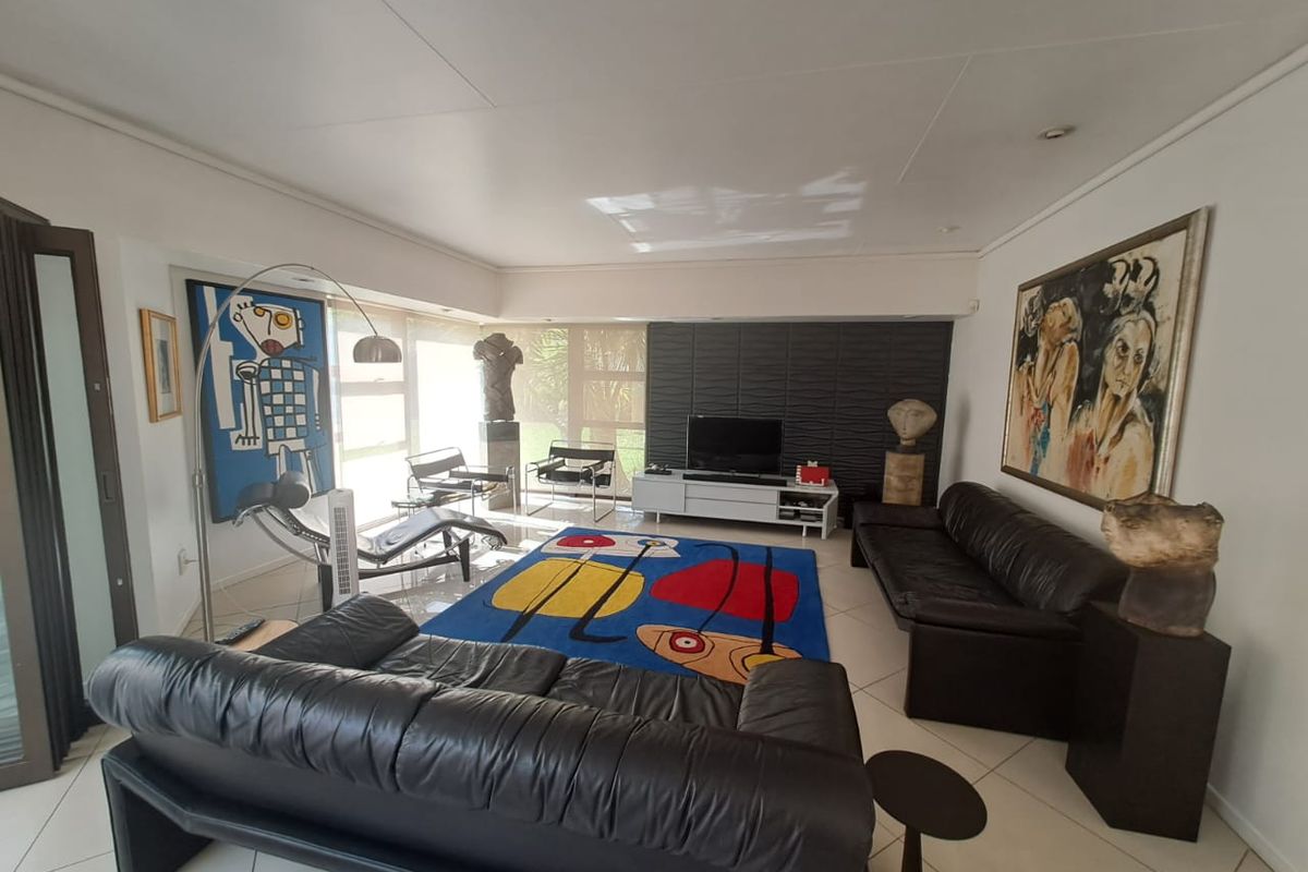 Spacious living room featuring large windows, tiled flooring, and a textured feature wall, offering a bright and contemporary atmosphere.