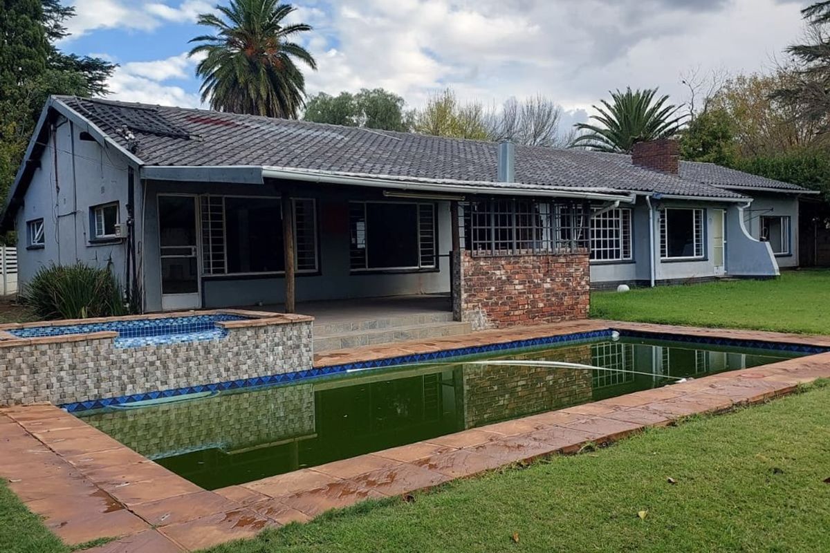 Rear view of the house featuring a swimming pool with a raised spa, a covered patio area, and a spacious lawn.