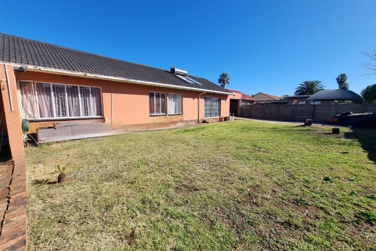 A spacious rear garden featuring a lawn area and the rear elevation of the house, complete with a solar water heating system.