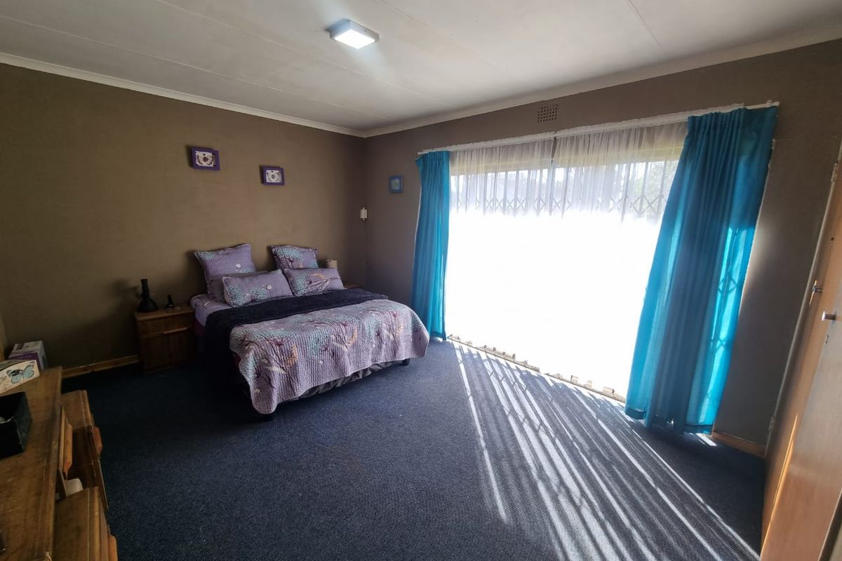 Spacious bedroom featuring large sliding glass doors with security gate, providing ample natural light and direct access to the exterior.