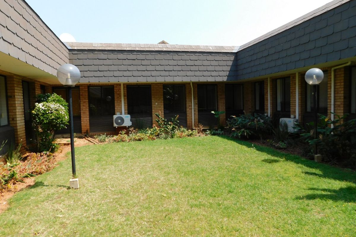 A central courtyard garden area featuring a lawn, perimeter landscaping, and exterior building access with mounted air conditioning units.