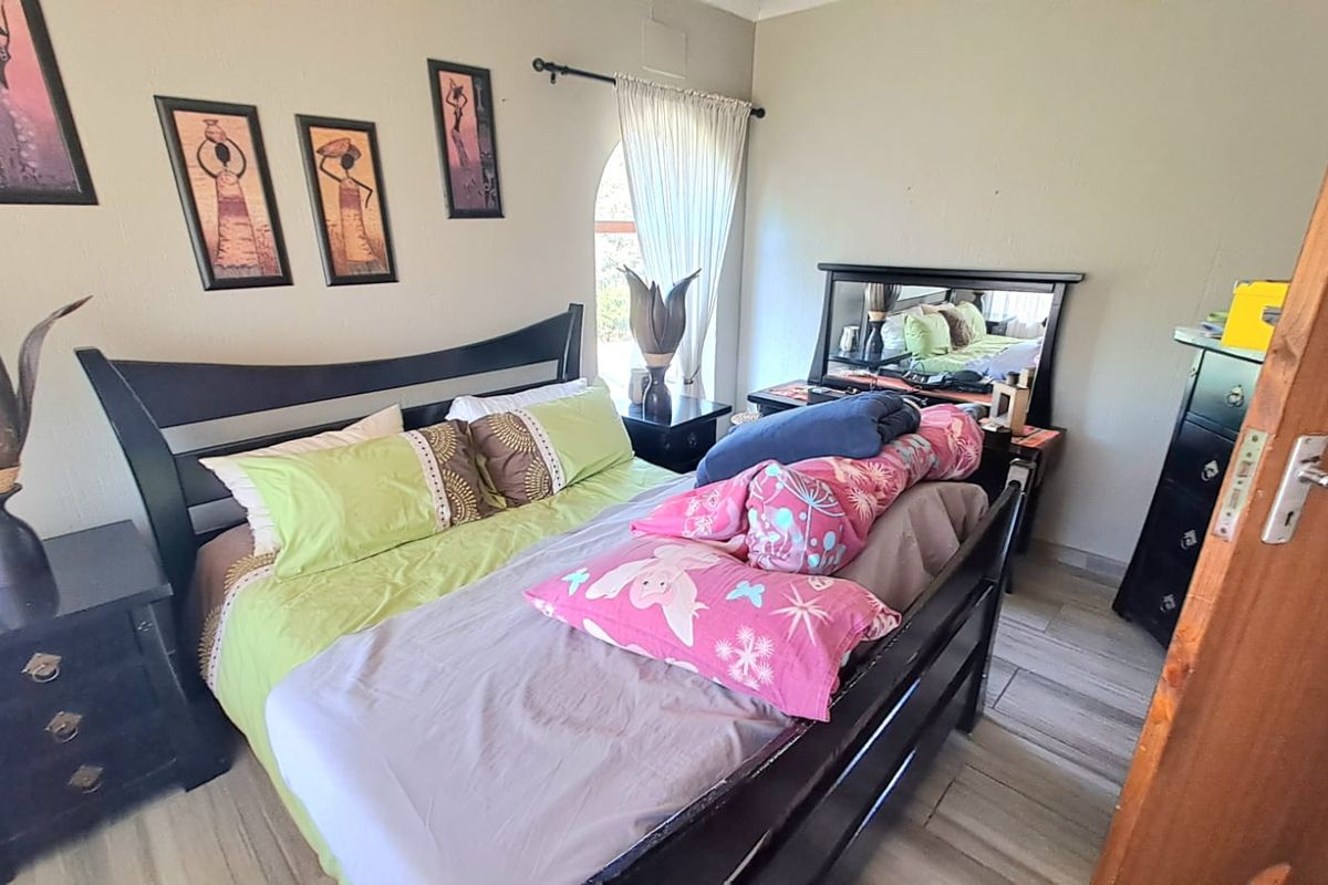 A standard bedroom featuring tiled flooring, an arched window with curtain rod, and neutral wall paint.