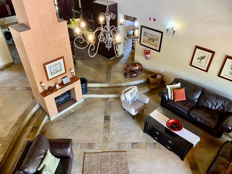 Spacious open-plan living area featuring a central fireplace, raised platform design, and elegant chandelier lighting, creating a warm and inviting atmosphere.