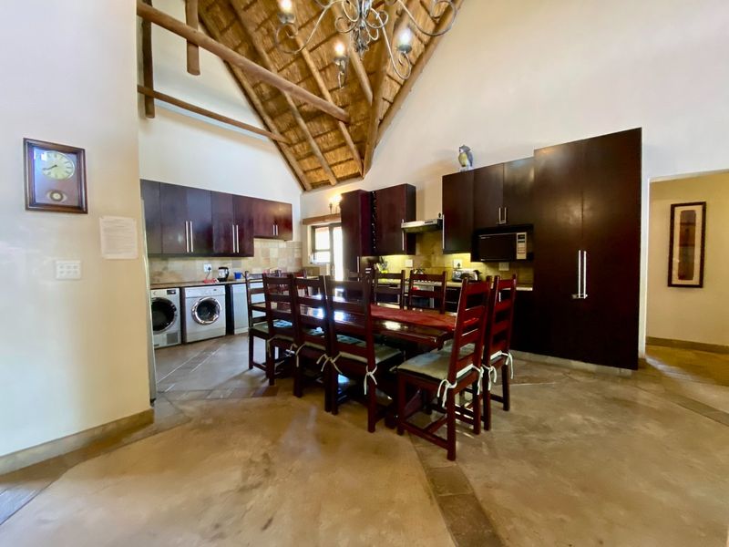 Open-plan kitchen and dining area featuring a high vaulted thatched ceiling with exposed timber beams and dark wood cabinetry.