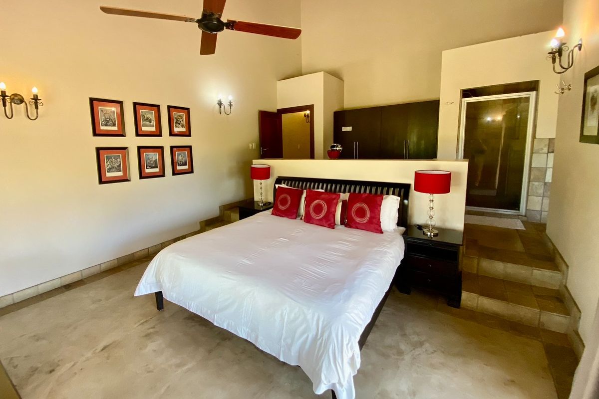 Spacious bedroom featuring high ceilings, a ceiling fan, built-in cupboards, and an open-plan layout with direct access to an en-suite bathroom.