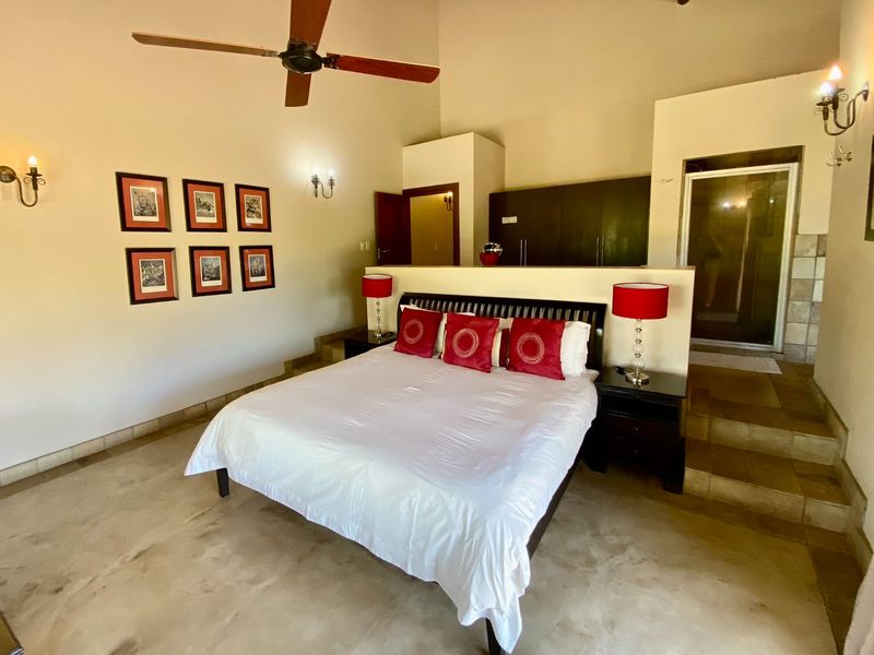 Spacious bedroom featuring high ceilings, a ceiling fan, built-in cupboards, and an open-plan layout with direct access to an en-suite bathroom.