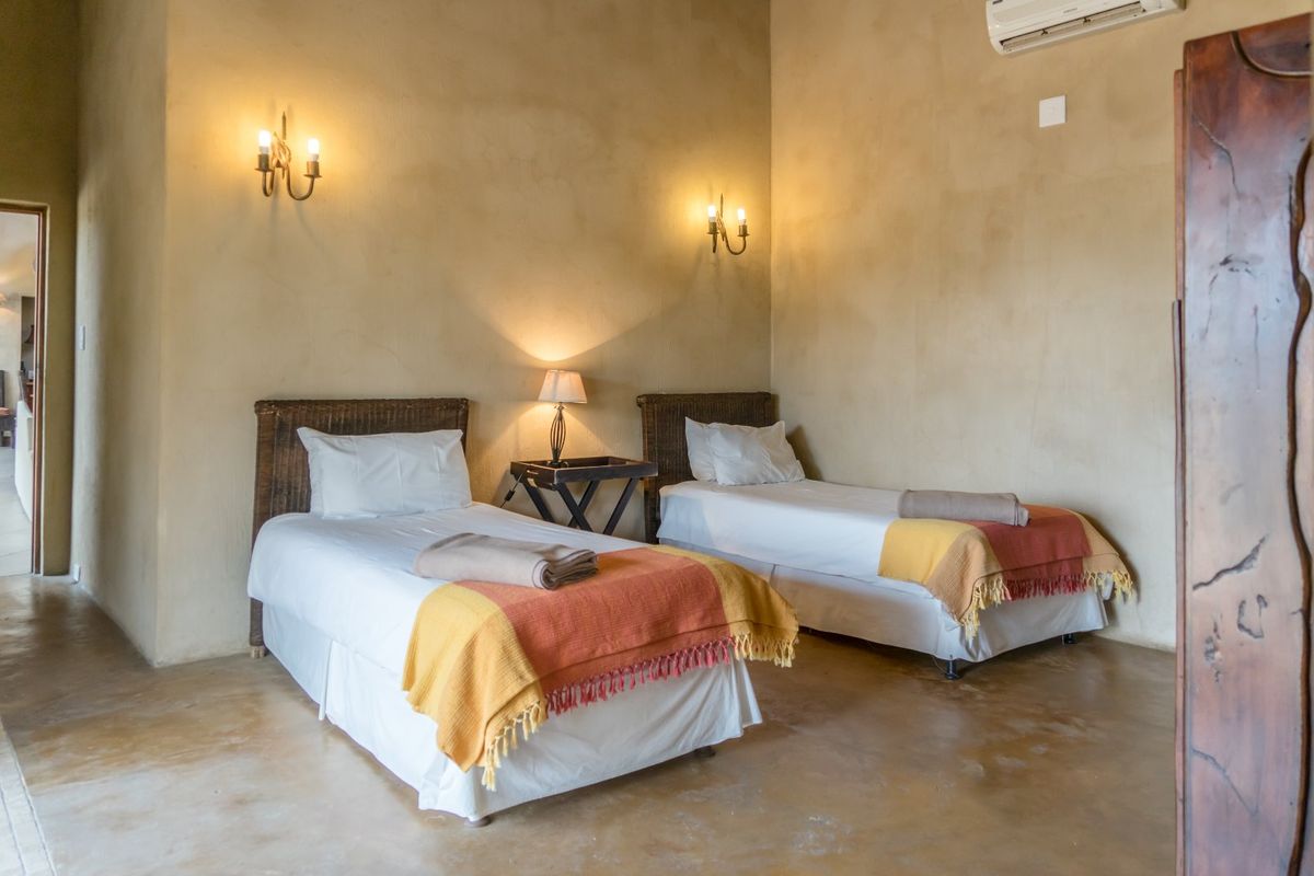 A bedroom featuring polished concrete floors, textured walls, and wall-mounted lighting fixtures with an integrated air conditioning unit.