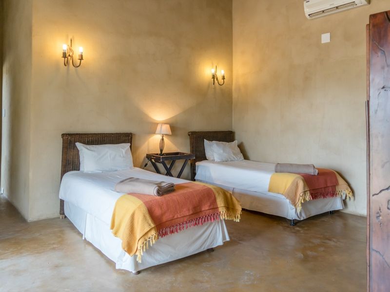 A bedroom featuring polished concrete floors, textured walls, and wall-mounted lighting fixtures with an integrated air conditioning unit.