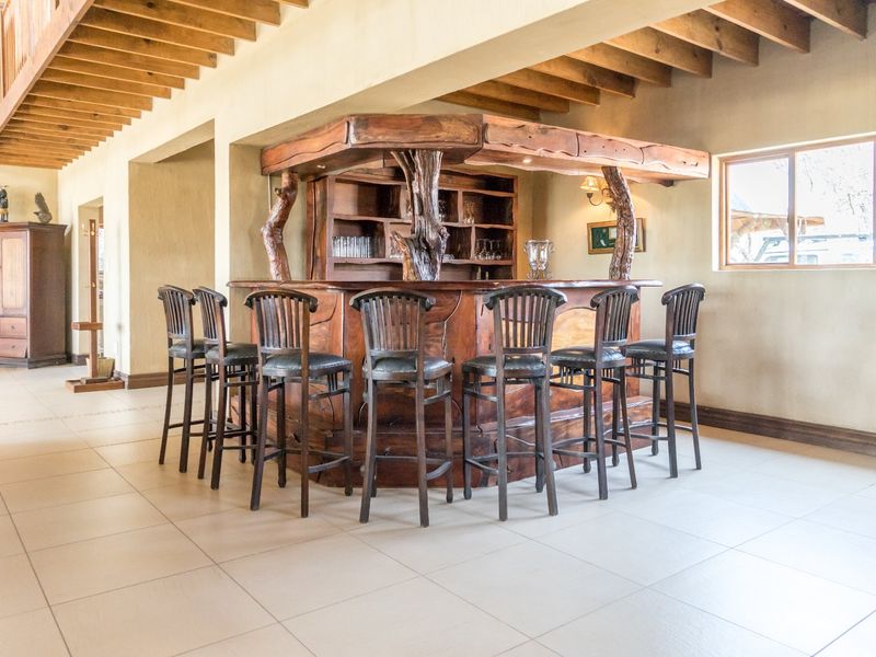 A rustic-style built-in wooden bar area featuring exposed timber ceiling beams and tiled flooring, creating a warm and inviting entertainment space.