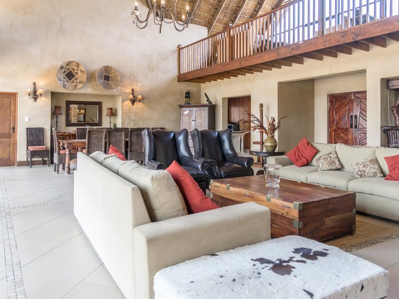 Spacious open-plan living area featuring a high vaulted thatched ceiling, exposed timber rafters, and a mezzanine level with a wooden balustrade.