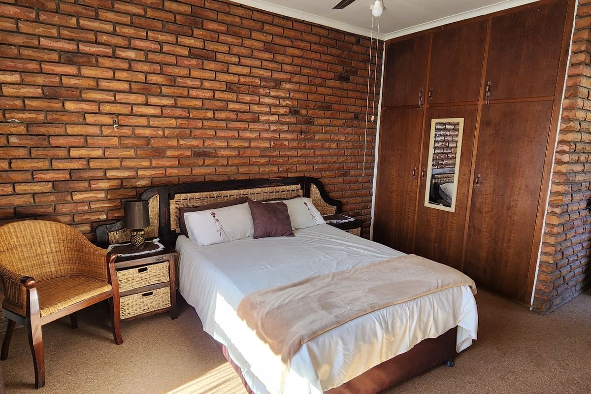 A bedroom featuring a rustic exposed brick feature wall and built-in wooden cupboards.