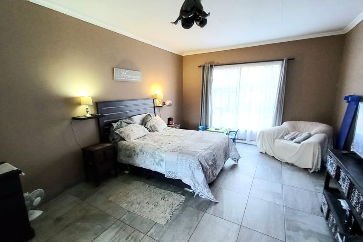 Spacious bedroom featuring large format floor tiles, sliding glass doors providing natural light, and a neutral color palette.