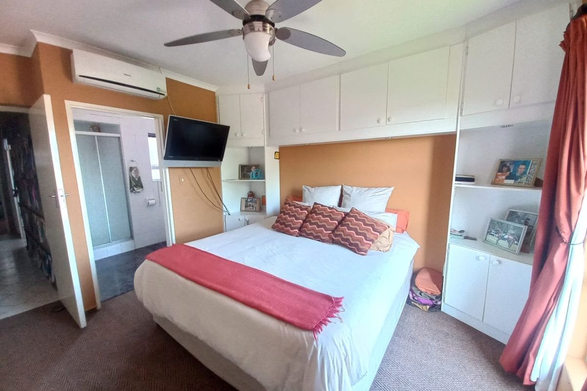 A bedroom featuring built-in cabinetry surrounding the bed area, a ceiling fan, and an en-suite bathroom access.