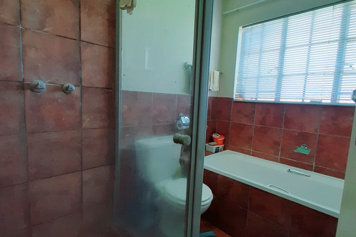 A functional bathroom featuring a glass-enclosed shower, a built-in bathtub, and tiled wall finishes.